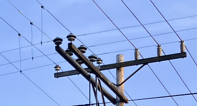 Sets of 3 electrical wires, intersecting at the top of a light pole