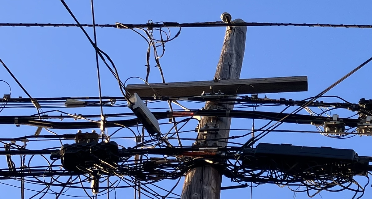 Jumbled telecommunication wires at the top of a pole